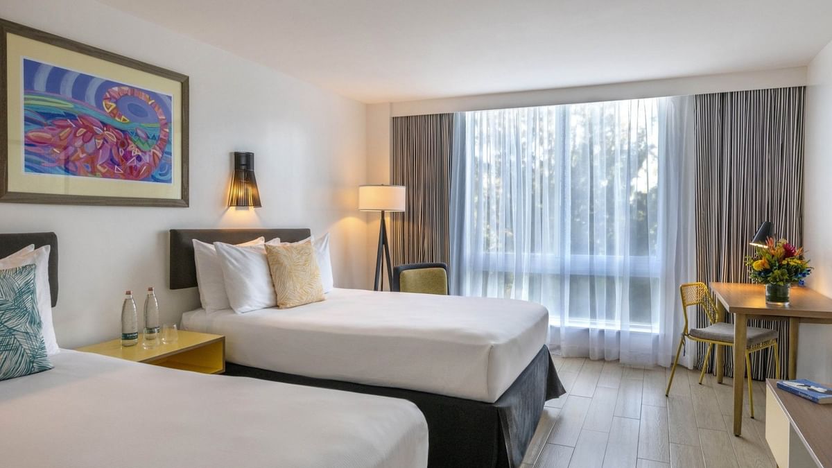 Twin beds by a wooden desk and chair under a floor in Island View at Warwick Paradise Island Bahamas