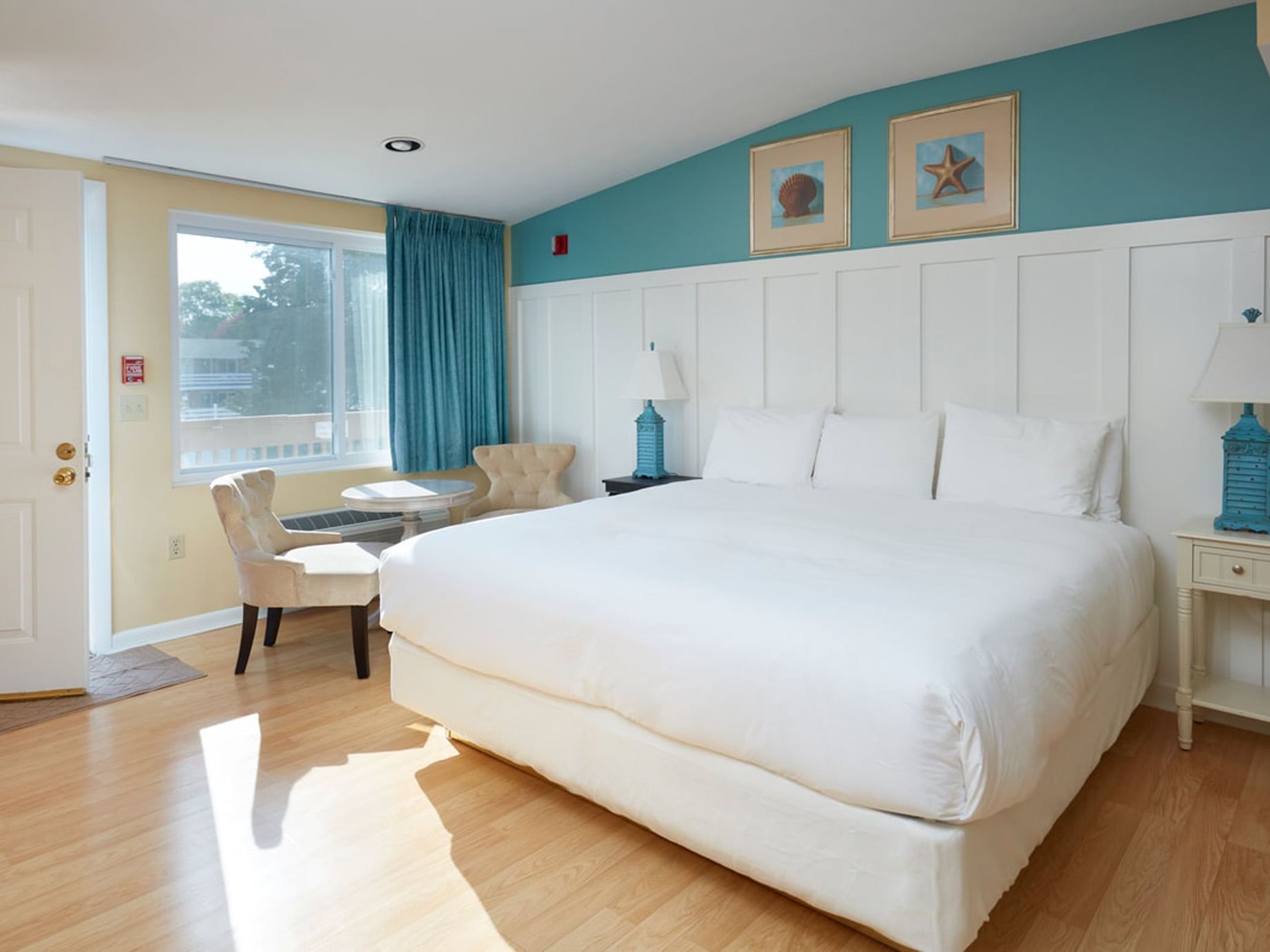 Bed with seating by the window and wooden floors in Anika Cottage Suite at Breezeway Boutique Hotel