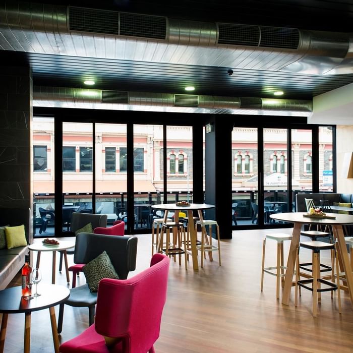 Level One Bar featuring modern seating, high tables, and windows leading to a balcony with city views at Ibis Adelaide