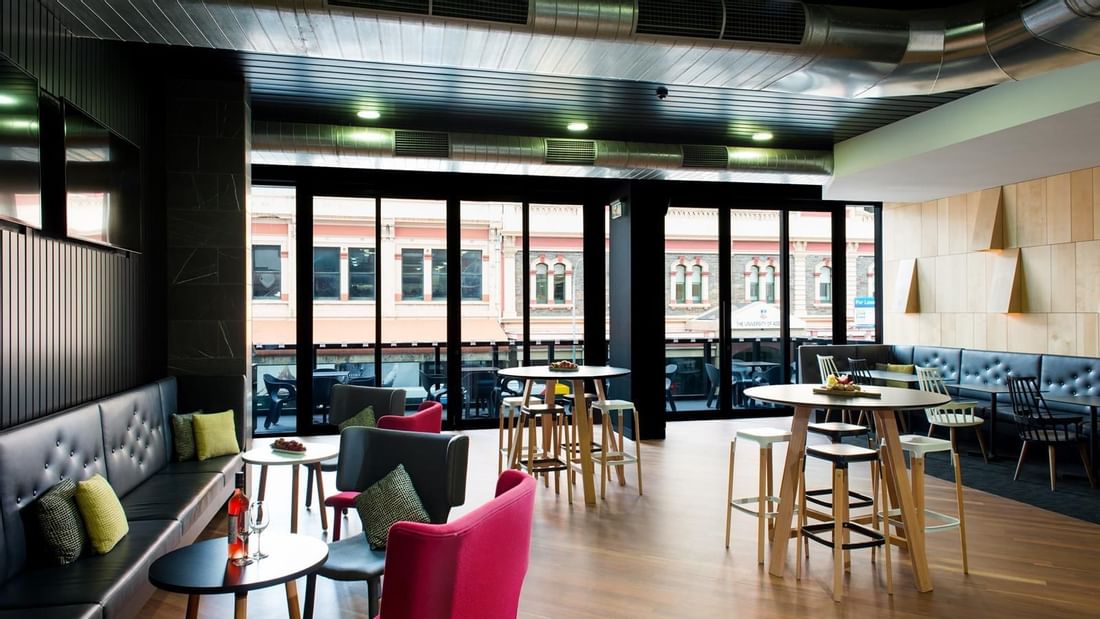 Level One Bar featuring modern seating, high tables, and windows leading to a balcony with city views at Ibis Adelaide