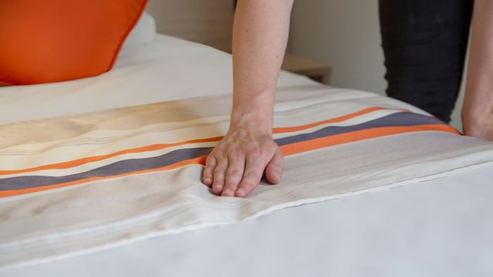 A Woman preparing a Standard bed at Le Clos de l'Orgerie