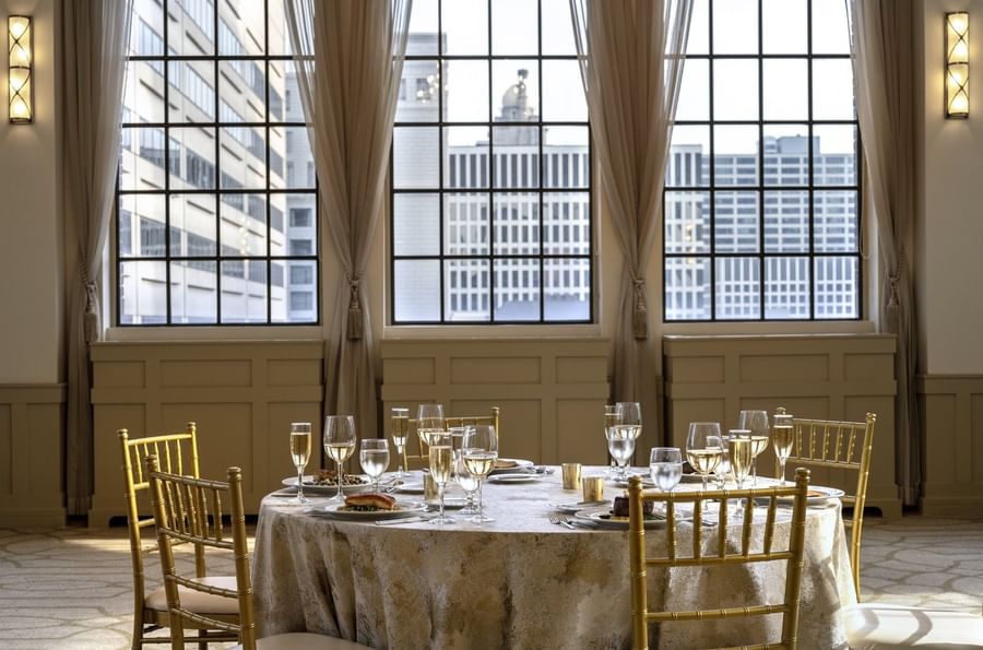 Elegantly set dining table with cityscape view through large windows at Warwick Allerton Chicago