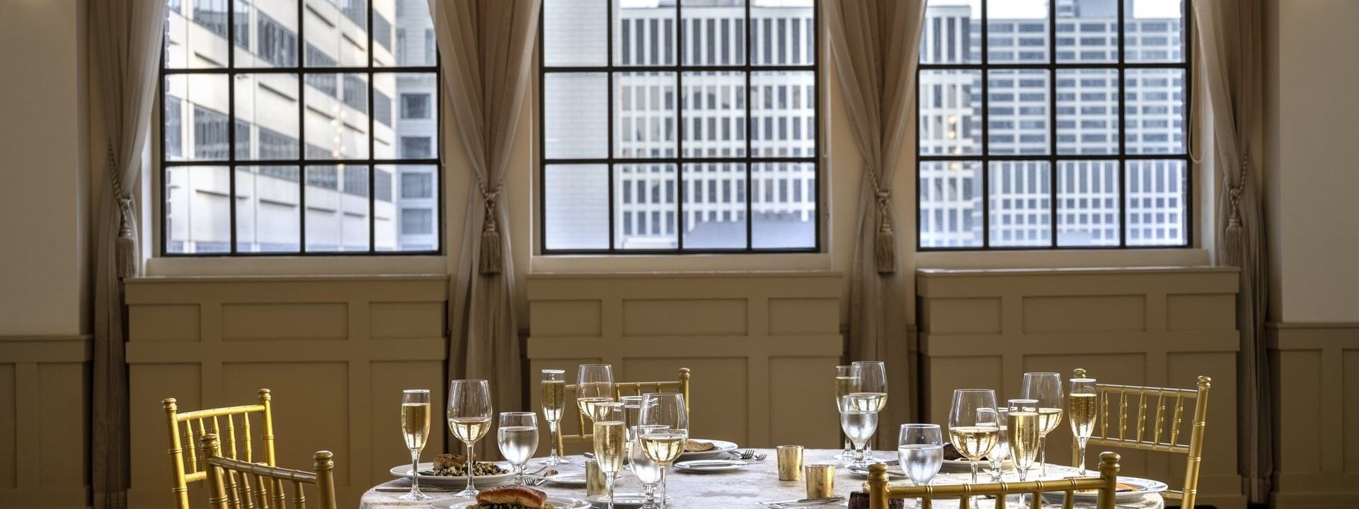 Round dining table with wine glasses, placed by windows in 	
Huron Room at Warwick Allerton Chicago