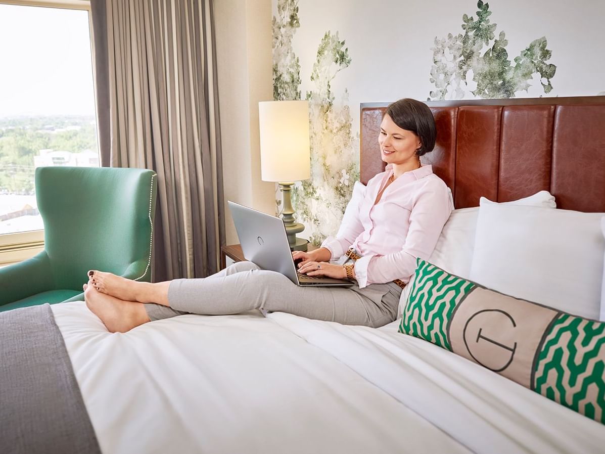A lady using a laptop on a bed at The Grove Hotel
