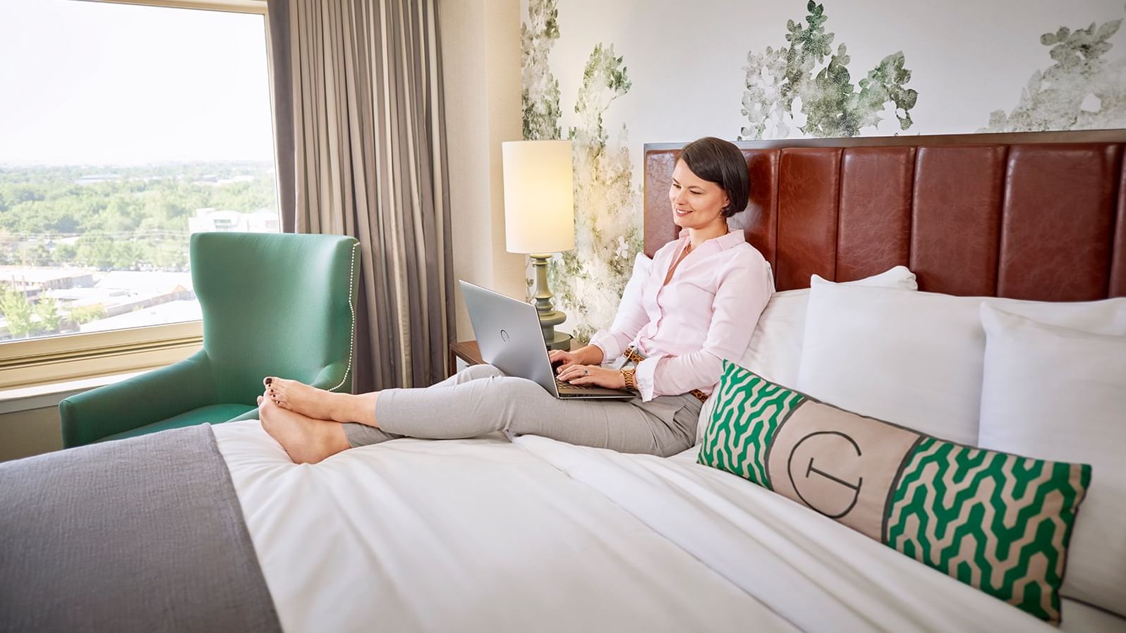 A lady using a laptop on a bed at The Grove Hotel