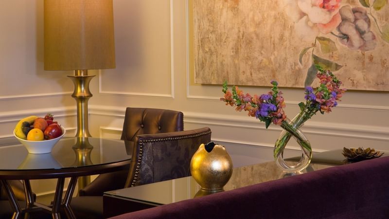 Dinning table with velvet chair & gold vase with fruit bowl, and flower arrangement in Follie Suite at Warwick New York