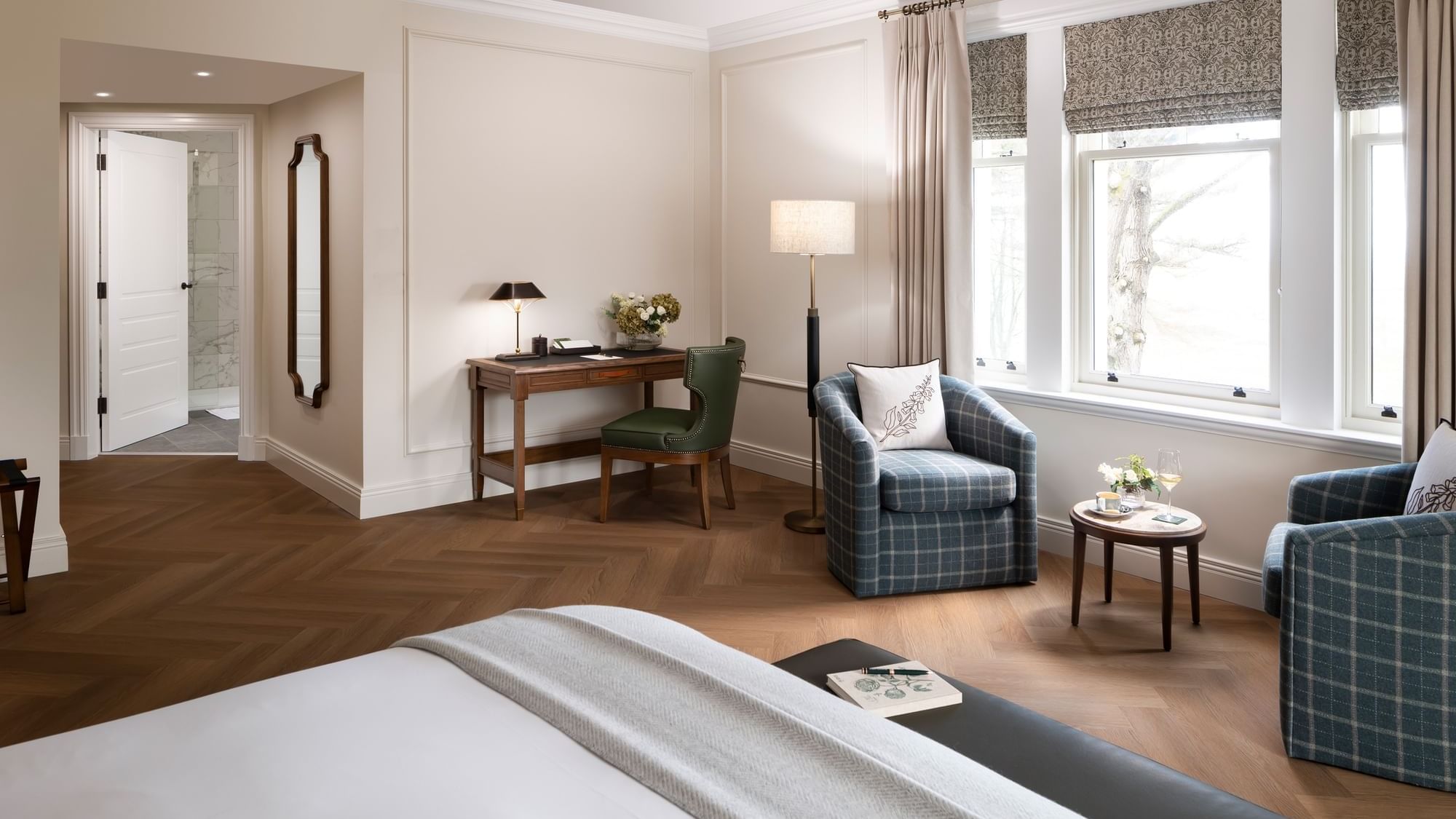Bed with work desk and seating area by the window in Portrush Suite at Dunluce Lodge