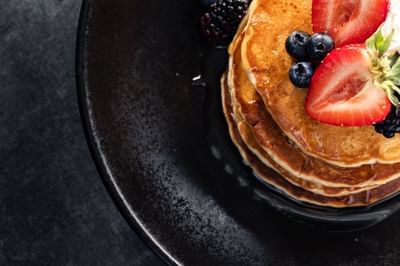 Golden-brown stack of pancakes topped with fresh strawberries and blueberries served at The Boulevard Inn & Bistro