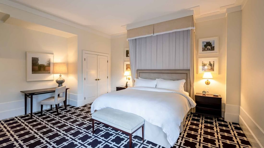 Work desk and ottoman by the cozy bed in Deluxe King Mobility and Hearing Accessible with Roll In Shower at El Prado Hotel