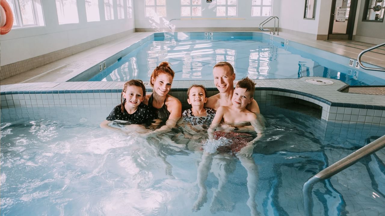 A happy family enjoying a relaxing moment in the hot tub at Coast Canmore Hotel & Conference Centre.