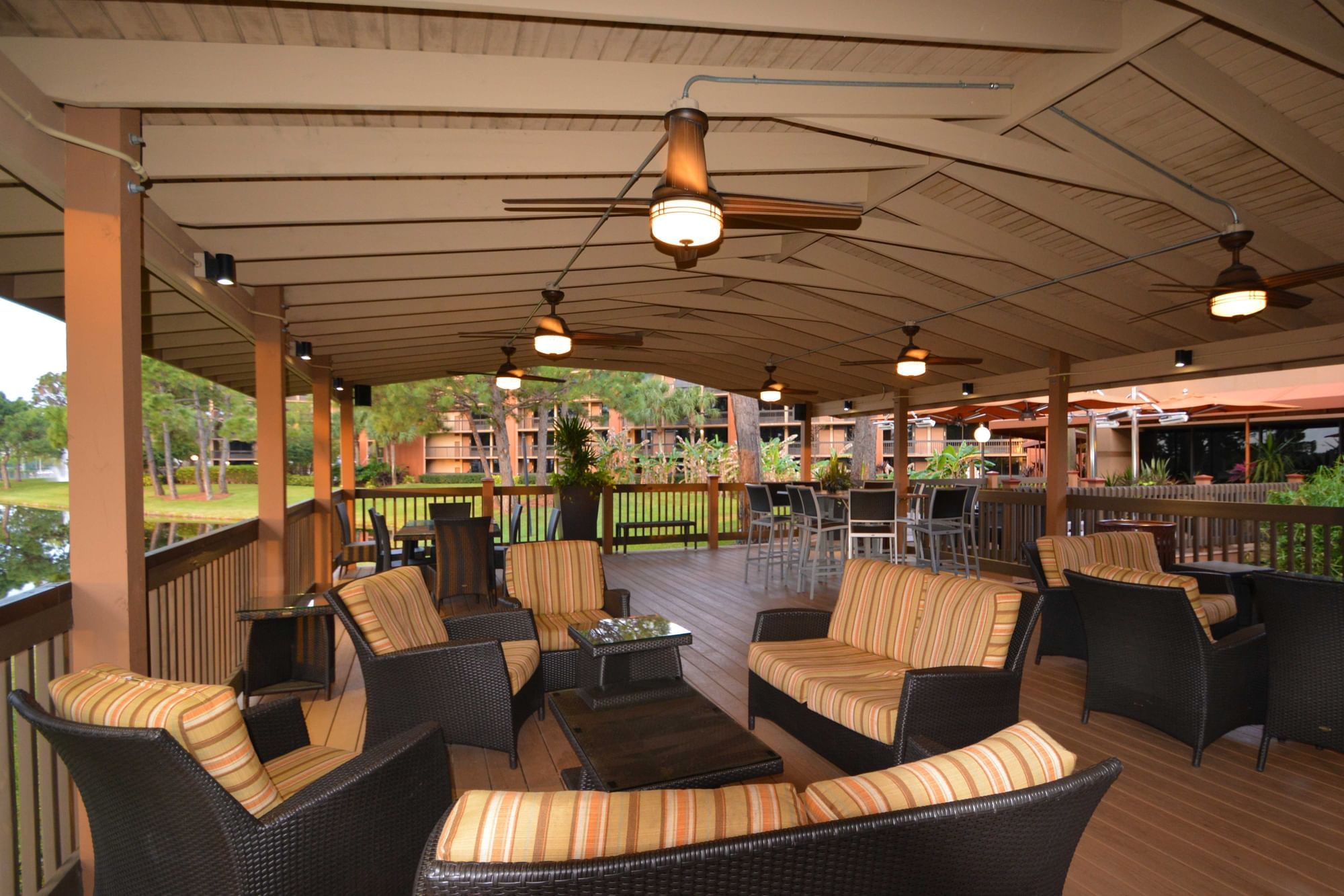 A covered outdoor seating area with wicker furniture and ceiling fans.
