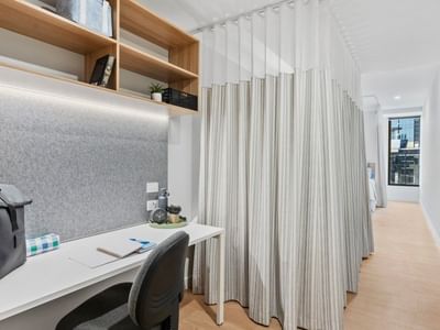 Modern hotel room workspace with desk, chair, and curtain divider at UniLodge Brisbane City.