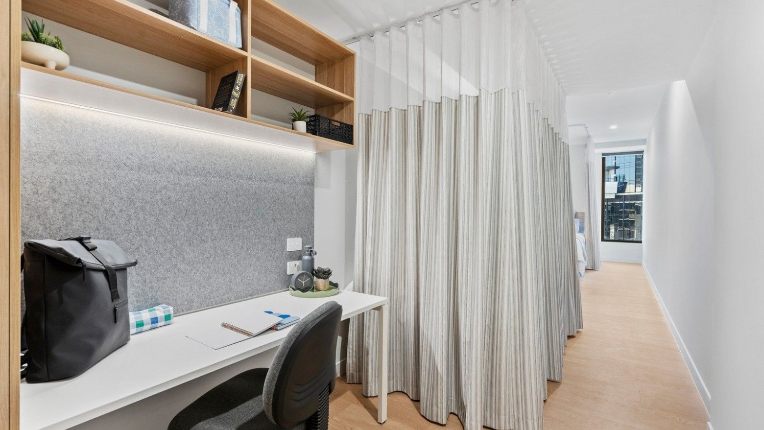 Modern hotel room workspace with desk, chair, and curtain divider at UniLodge Brisbane City.
