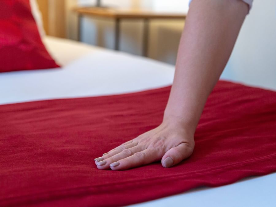 A maid preparing a bed in a room at Hotel Saint-Laurent