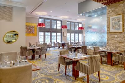 Firewater Grille interior featuring stone walls, water fountain, round wooden tables, and chairs at Duxton Hotel Perth