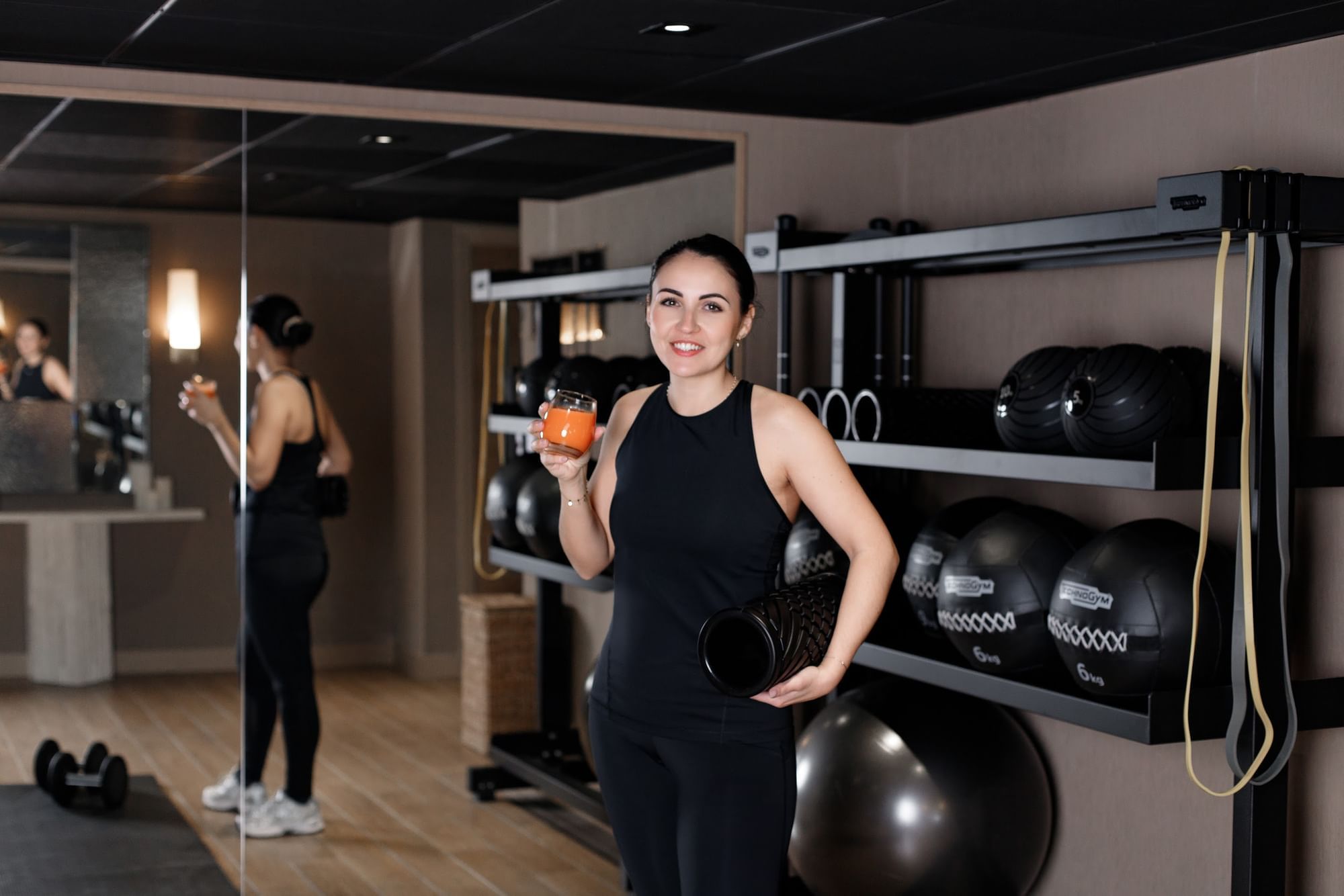 Woman holds a drink and a foam roller in Fitness Centre at Warwick Reine Astrid - Lyon