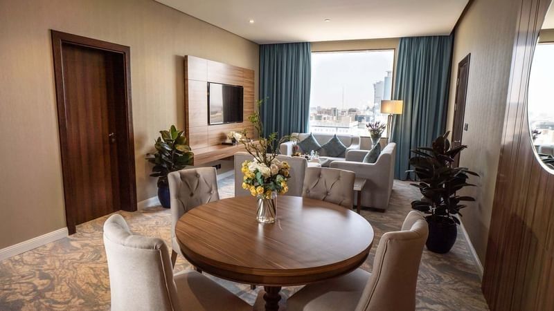 Executive Suite features Round wooden table with chairs by a living area at Cantonal Hotel by Warwick Riyadh
