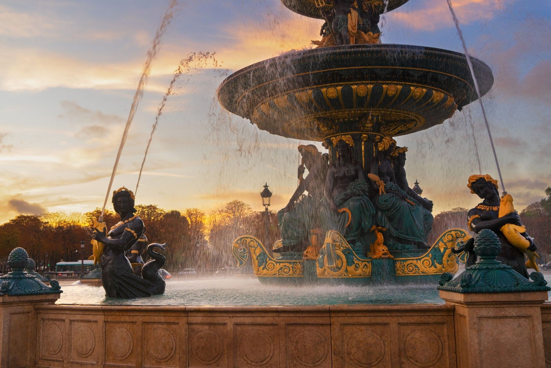 Grand fountain by ornate statues under a sunset sky surrounding the historic square at Warwick Paris Champs Elysées