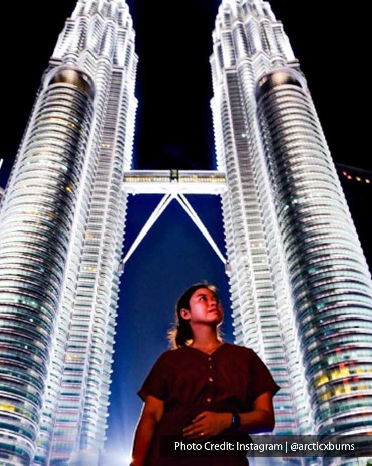 Girl standing under The Petronas Twin Towers, famous twin skyscrapers near Imperial Lexis Kuala Lumpur