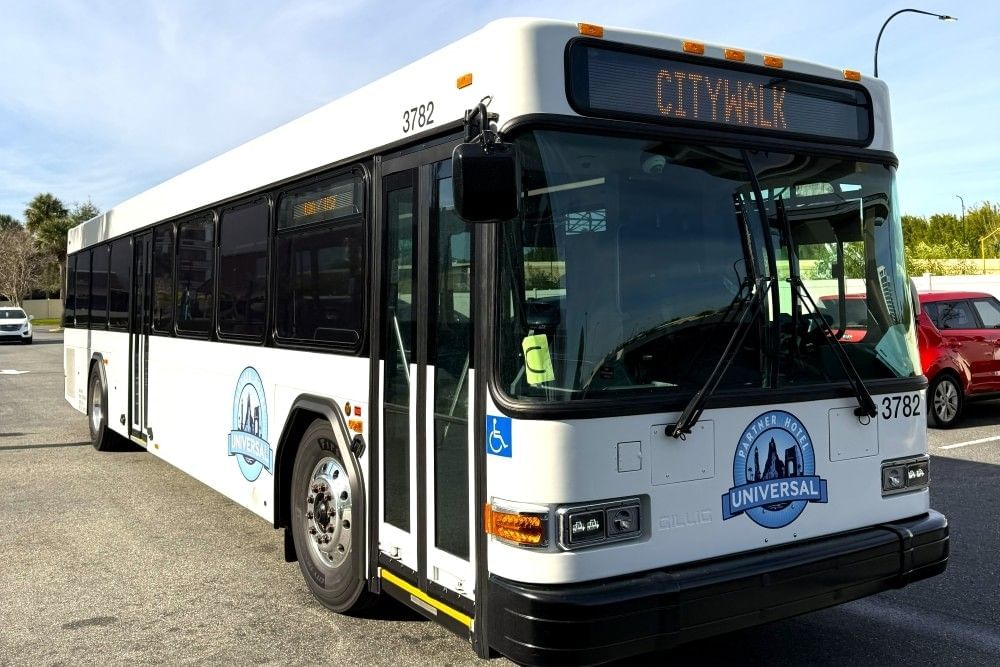 A photo of a large white bus with a digital sign reading CityWalk and branded with the blue Universal Partner Hotel logo.