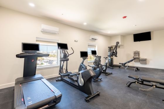 Modern gym with various exercise machines, brightened by natural light at The J Hotel