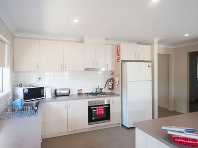 A clean kitchen with appliances and white cabinets at La Trobe University Regional Housing – Shepparton.