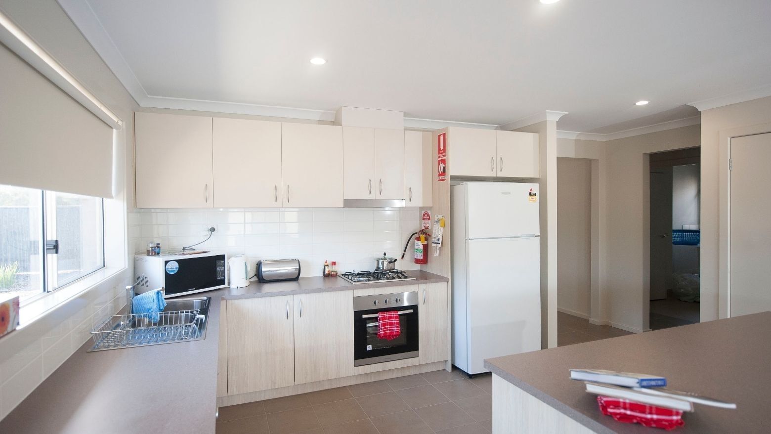 A clean kitchen with appliances and white cabinets at La Trobe University Regional Housing – Shepparton.