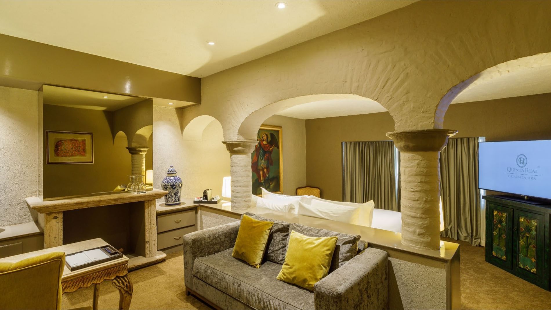 King Master Suite, detail with stone arches, grey sofa, and golden pillows at Quinta Real Guadalajara 
