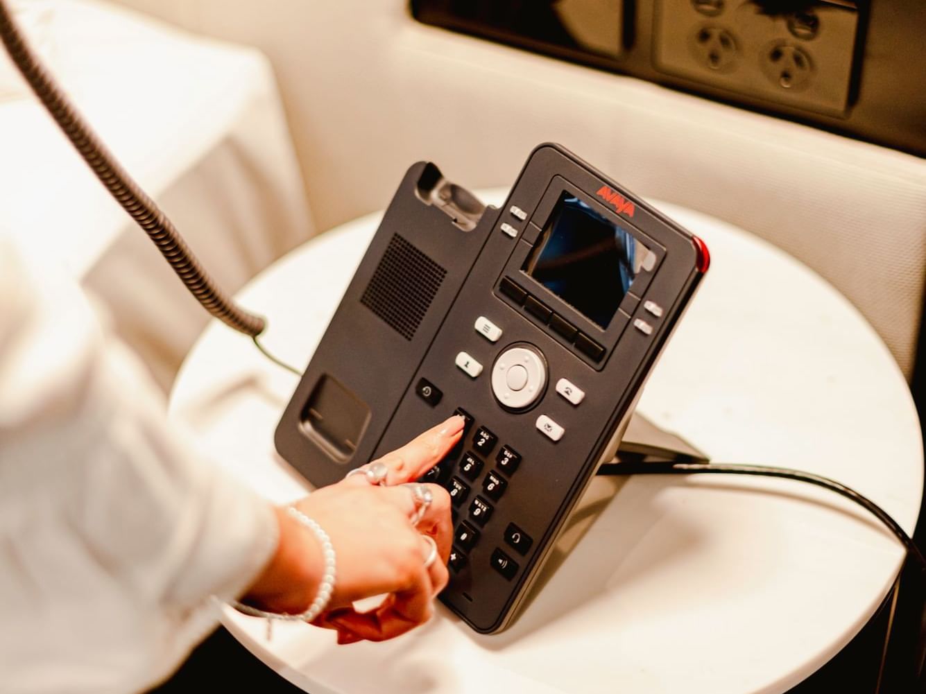 A lady using intercom telephone in a room at Brady Hotels