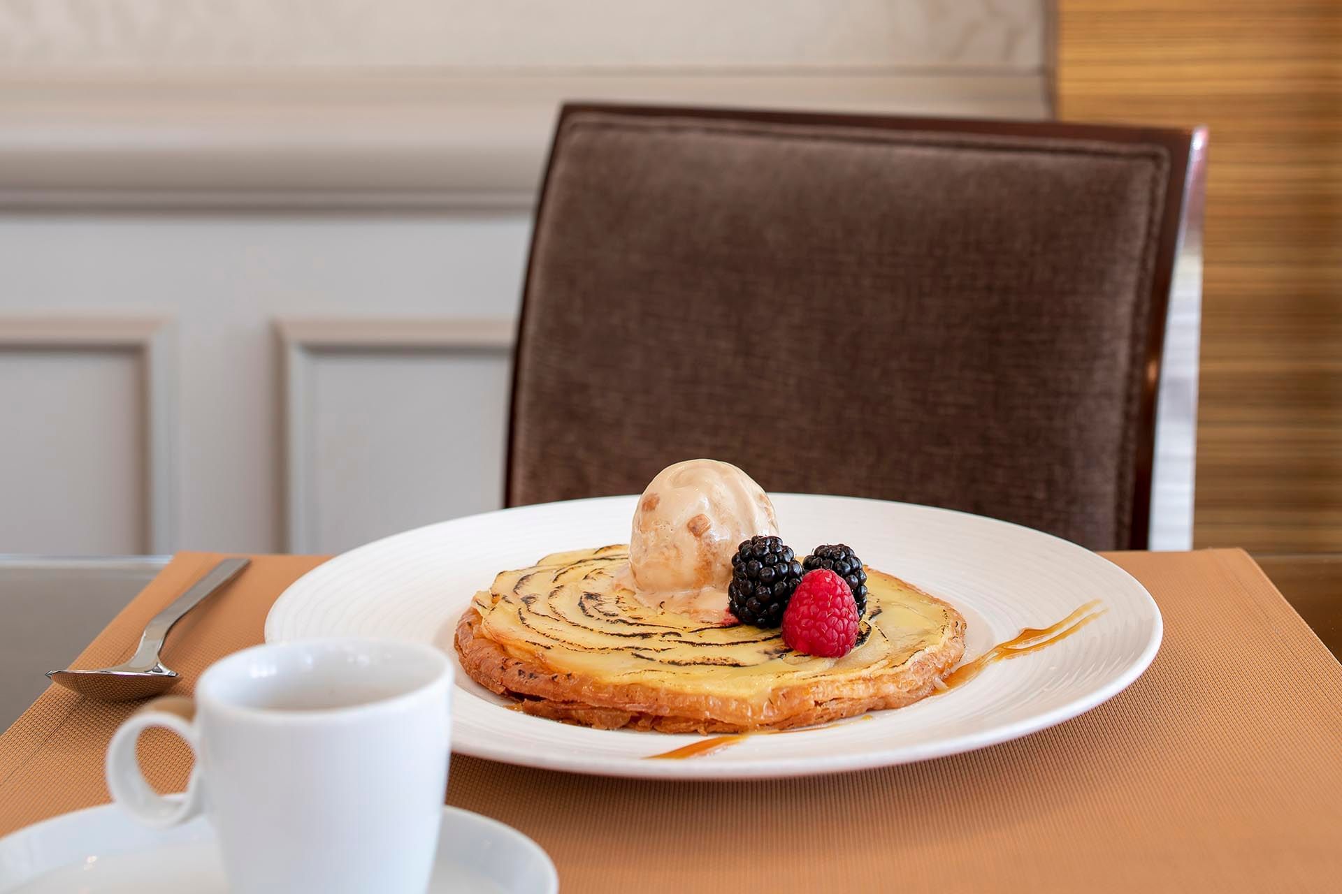 Plate with a golden pastry topped with a scoop of ice cream and fresh berries at Téséo Restaurant