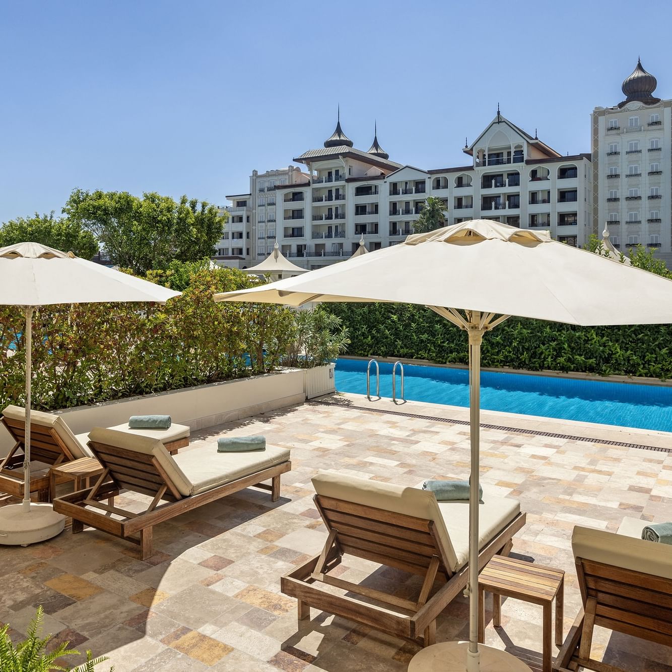 Premium Pool-Duplex-Suite im Titanic Mardan Palace – Liegestühle unter Sonnenschirmen am Pool.