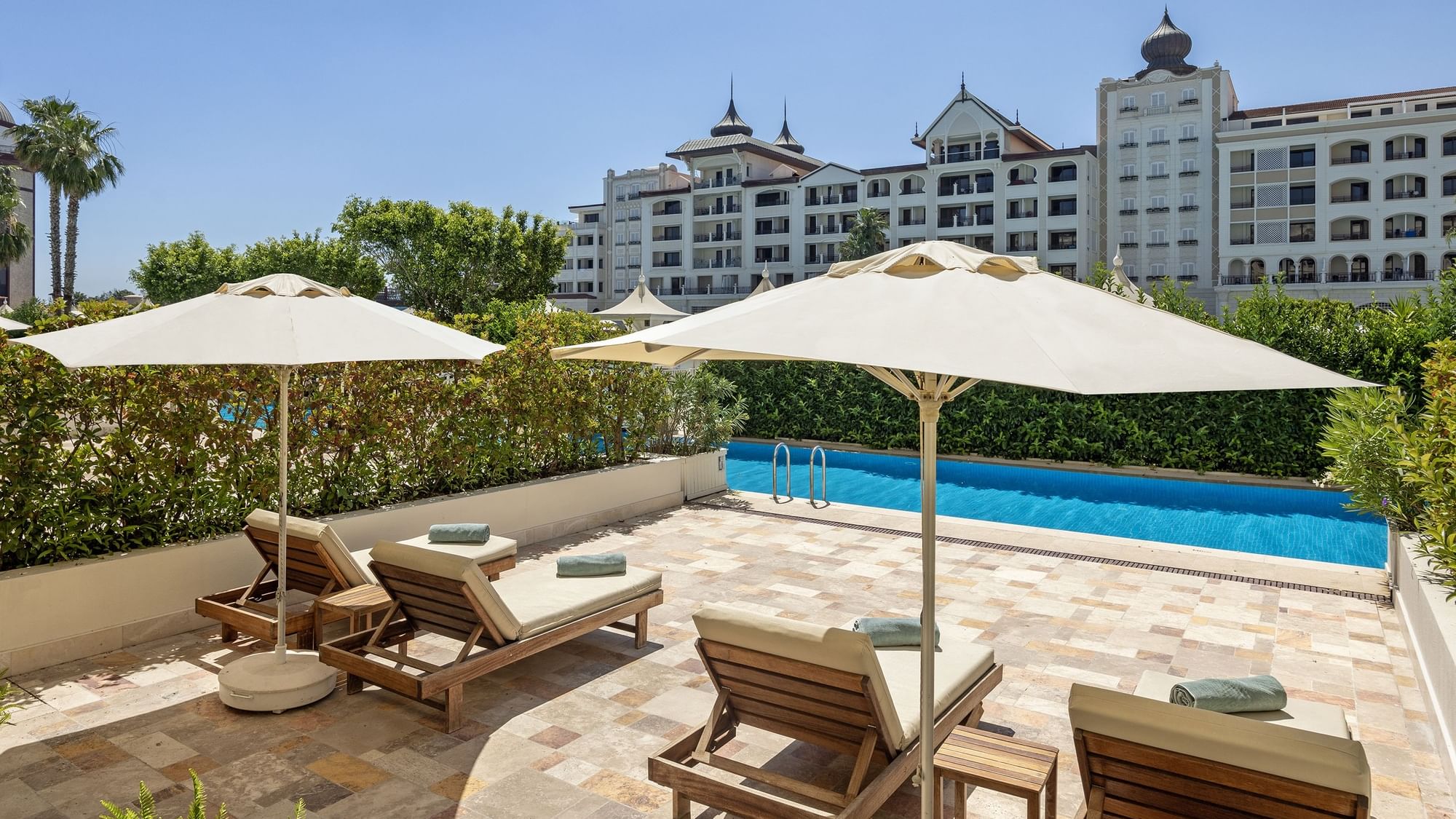 Premium Pool-Duplex-Suite im Titanic Mardan Palace – Liegestühle unter Sonnenschirmen am Pool.