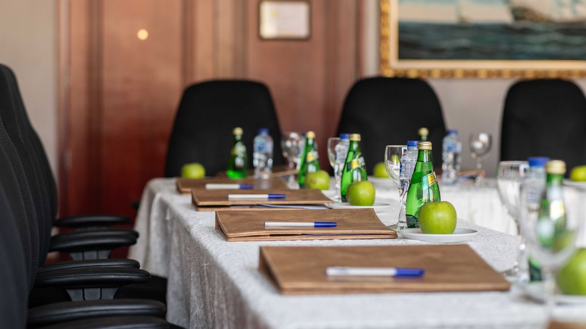 Amarige 4 conference table set with notebooks, pens, green apples, water bottles, and glasses, at Warwick Hotels and Resorts