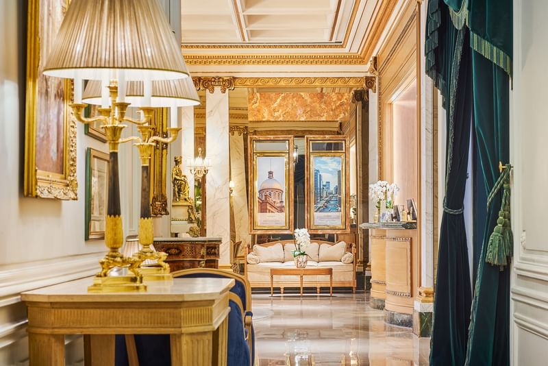Hall d'entrée luxueux avec colonnes en marbre, lustres dorés et canapé beige à l'Hotel Westminster Warwick Paris