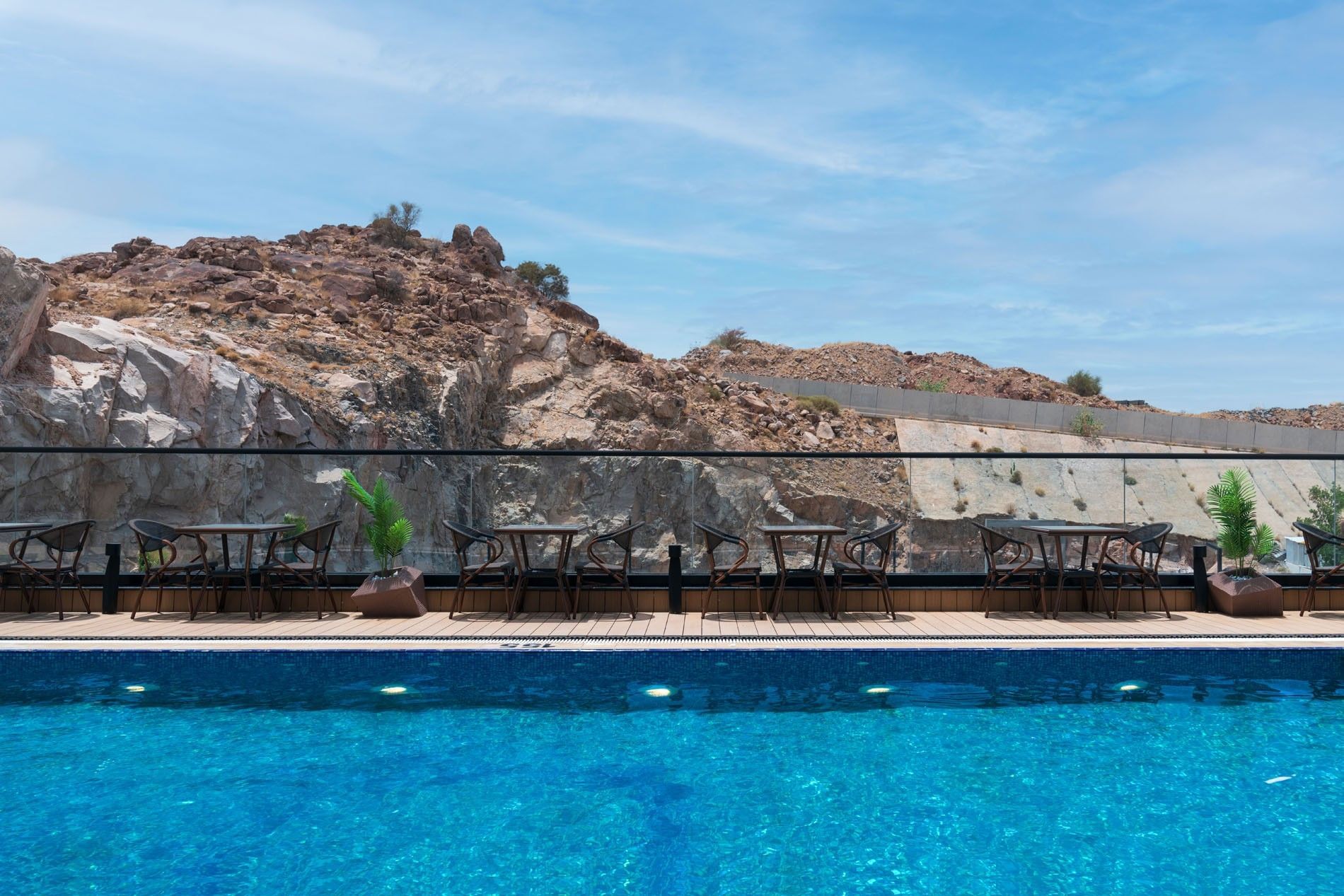 Rooftop swimming pool with lounge chairs and tables at Warwick Al Taif Hotel