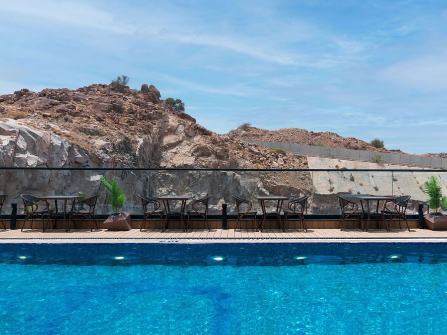 Rooftop swimming pool with lounge chairs and tables at Warwick Al Taif Hotel