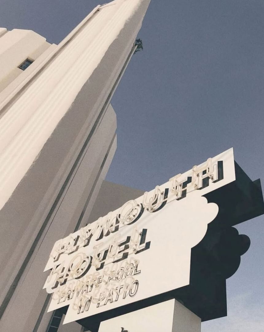 Low-angle view of the vintage white neon sign and the iconic Art Deco tower of The Plymouth Hotel South Beach