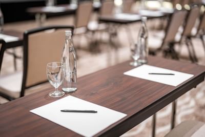 Classroom table arrangement with carpeted floors & a screen in the Meeting Room at Amora Hotel
