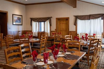 Dining area at The Ranch at Ucross, featuring a stone fireplace and multiple tables set with red napkins