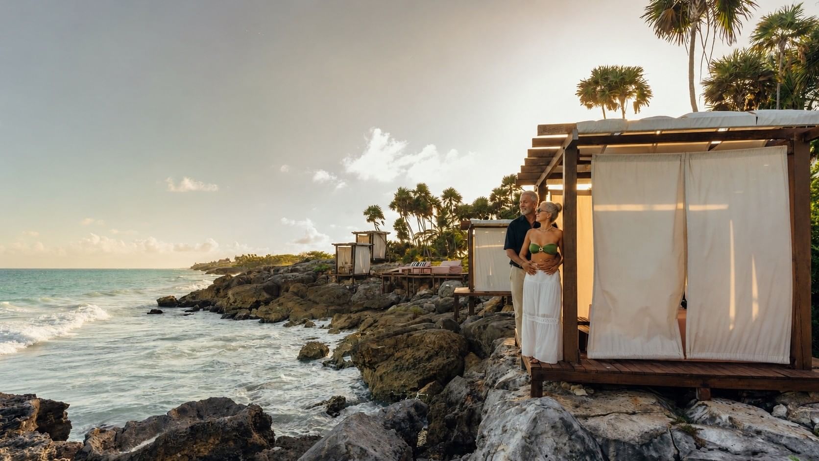 Couple embracing beside an oceanfront cabana at sunset at Mi Amor