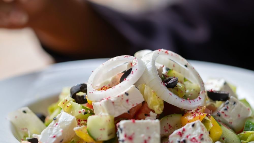 Close-up of a fresh salad featuring diced cucumber, onion rings, & feta cheese in Seasons Restaurant at Warwick Hotel Jeddah