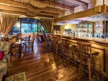 Bar counter by dining area in El Conquistador Bar with wooden floors at Porta Hotel Antigua