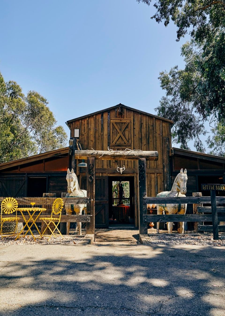 The Barn with yellow chairs by a small table in front of a barn at Elsewhere Topanga, ideal for Topanga Canyon events