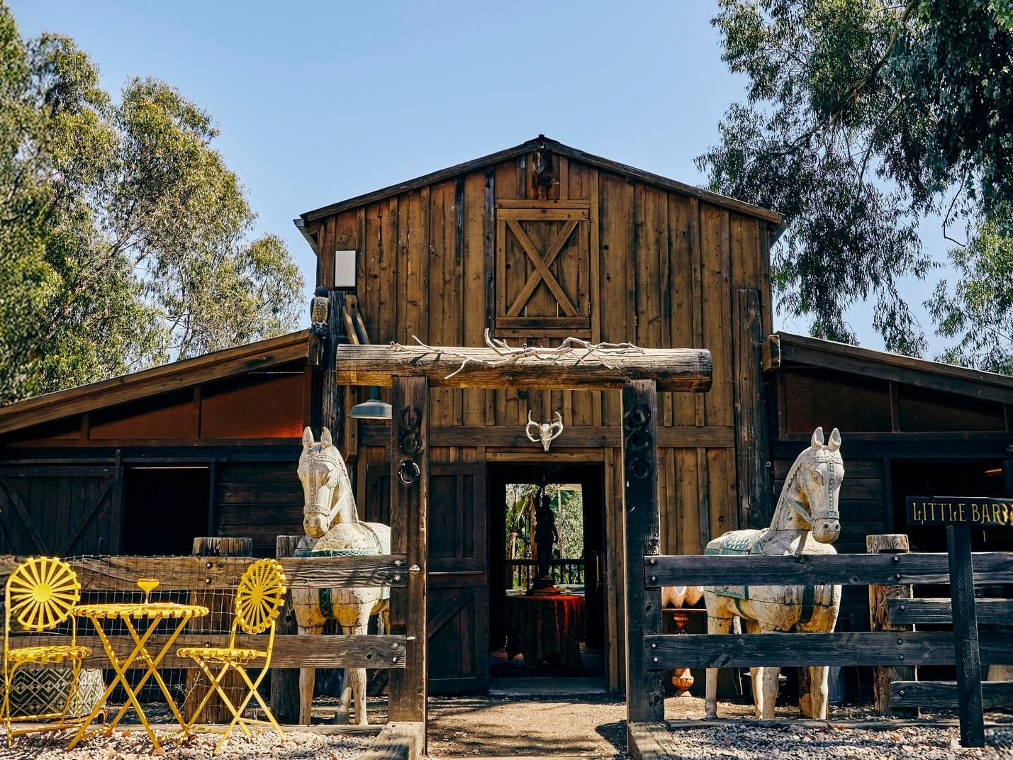 The Barn with yellow chairs by a small table in front of a barn at Elsewhere Topanga, ideal for Topanga Canyon events