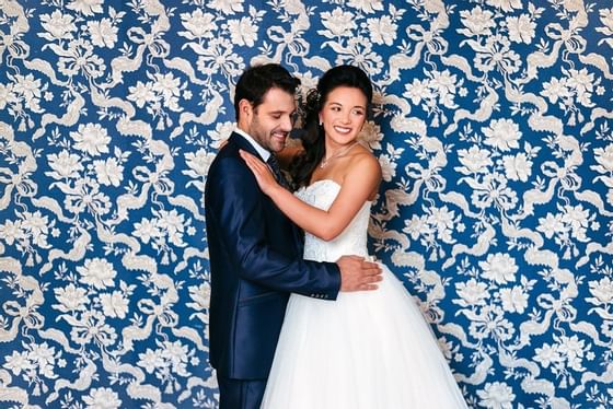 A wedding couple posing by a decorative wall at Schloss Hotel