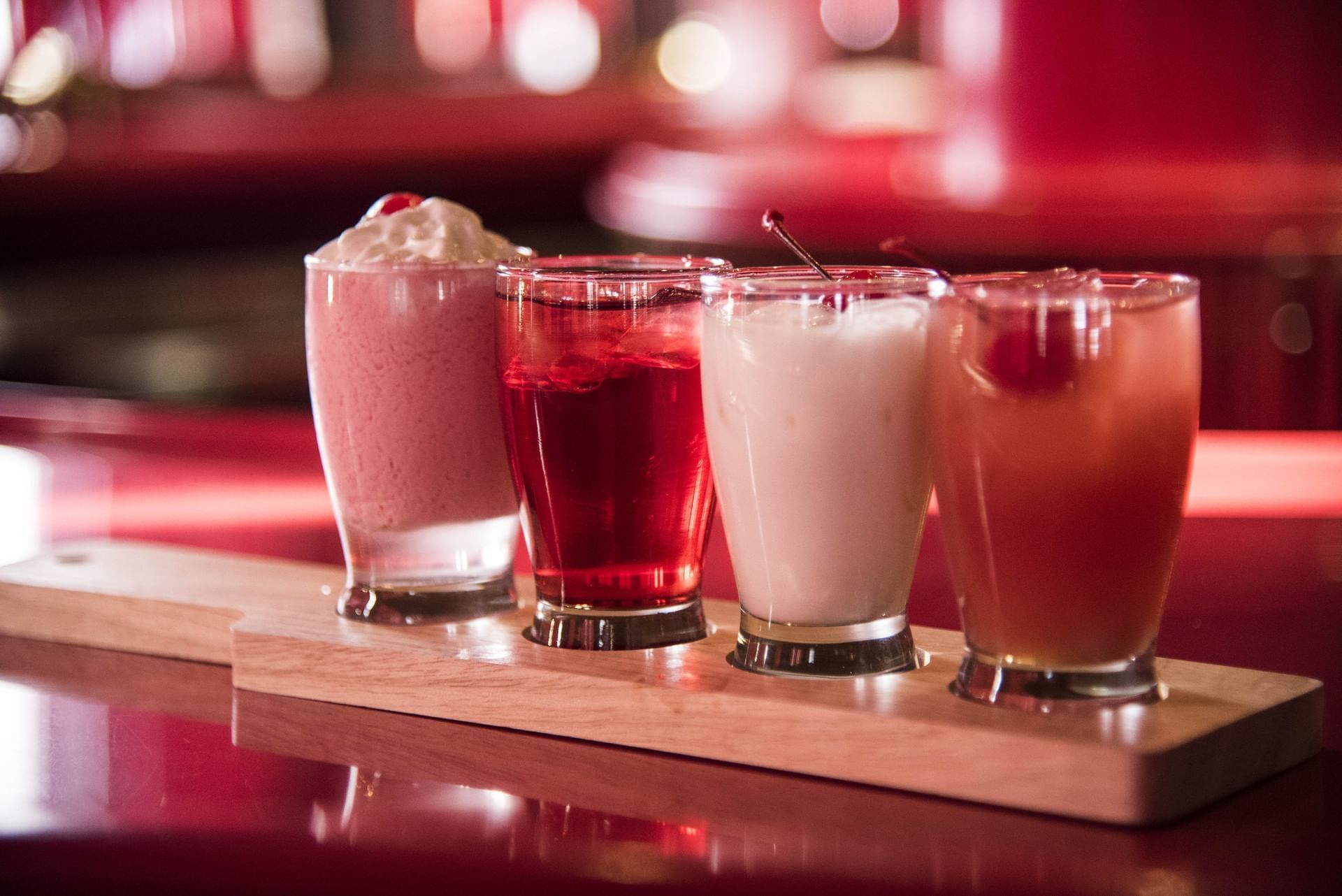 Four vibrant cocktails served on a wooden tray in the dining area at Cove Pocono Resorts