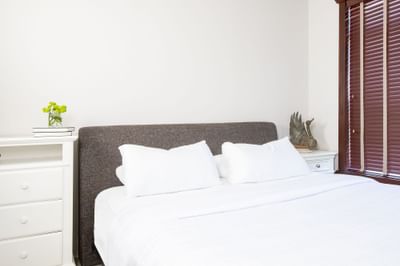 Cozy bed & bedside tables with plant in Apartment 406 at Retro Suites Hotel