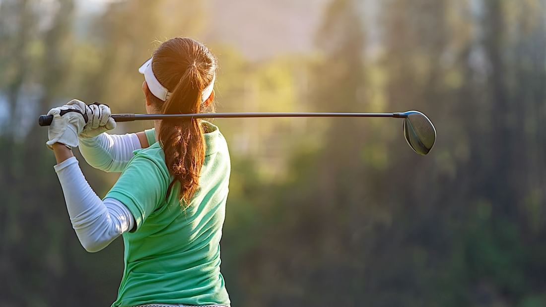 Woman golfer mid-swing on a sunny day at Baylands Golf Links, enjoying a leisurely round near El Prado Hotel