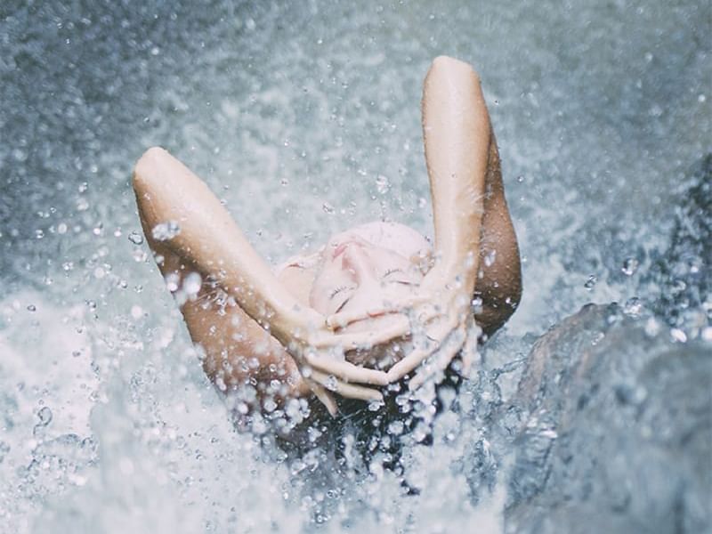 Low angle shot on lady under crystal waterfall near Costa Rica