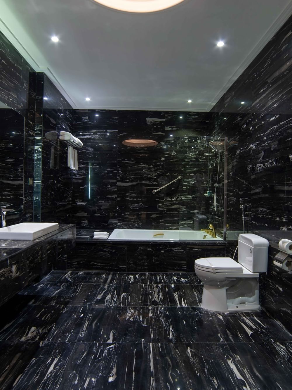 Penthouse Villa bathroom featuring black marble walls & floors with a built-in soaking tub at Warwick Al Khobar